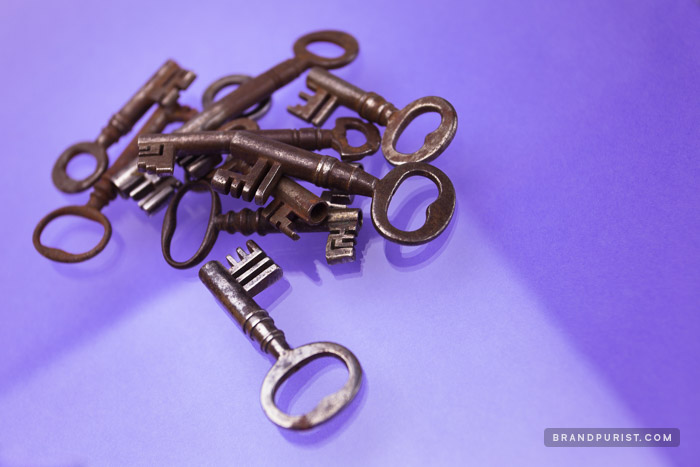 Rusty, old keys in a pile photographed on purple background.