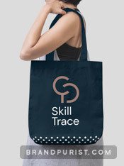 Young woman carrying a dark blue tote bag on her shoulder that features Skill Trace branding.