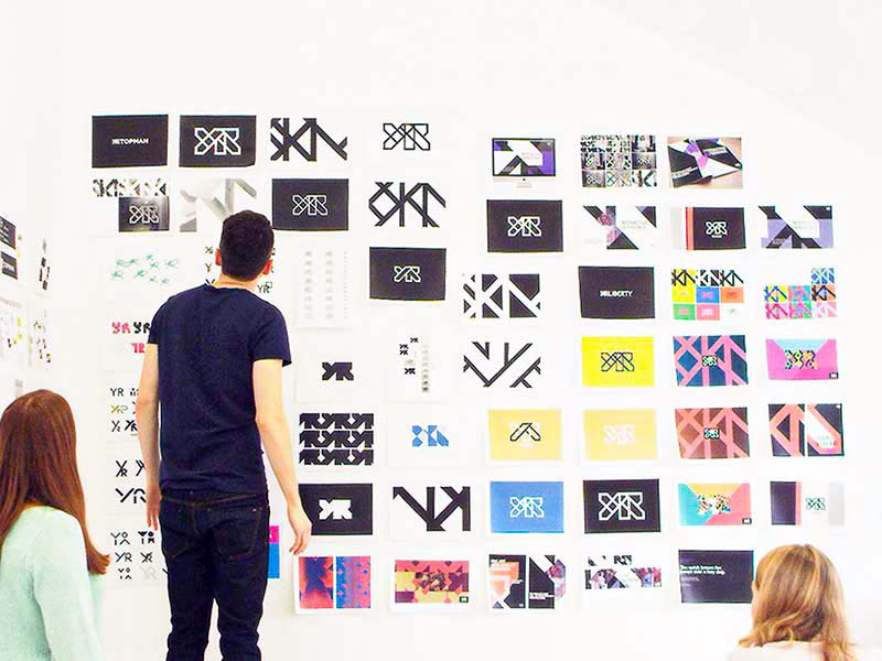 People in front of a wall covered in design development work.