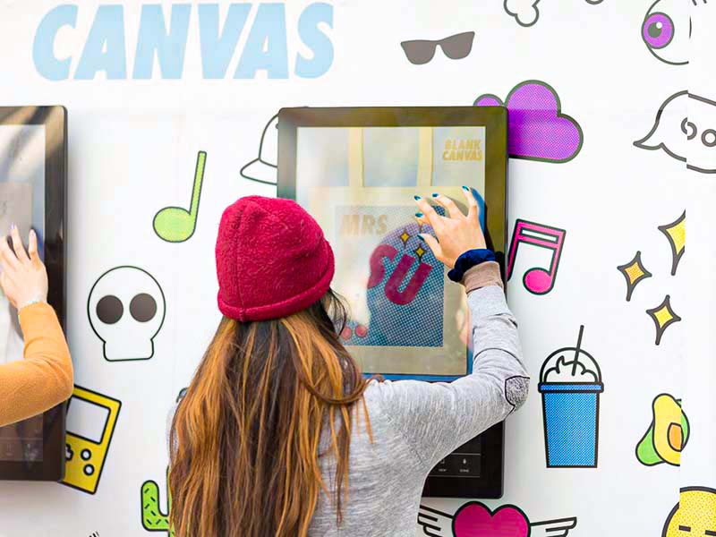 Girl interacting with a large touchscreen hung on a wall.