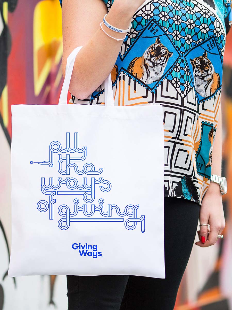 White tote bag which says 'All the ways of Giving' in a type design derived from the GivingWays logo mark.