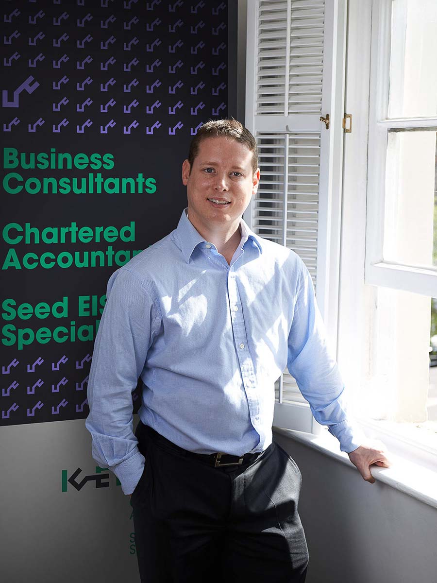 Photo of Gary Green, founder of Key Business Consultants, with a branded pull-up banner in the background.