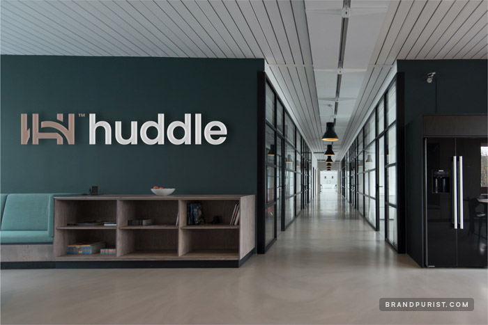 Huddle’s logo appearing as signage on the wall of a stylish office.