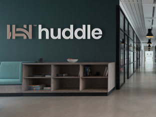 Huddle’s logo appearing as signage on the wall of a stylish office.