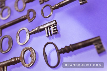 A set of small antique keys photographed on a purple background.