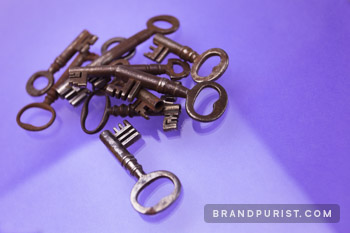 Rusty, old keys in a pile photographed on a purple background.