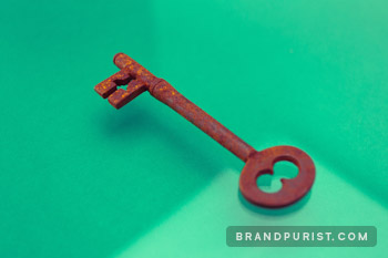 Photo of a rusty antique key set against a vibrant green background.