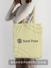 Young woman in front of a grey background carrying a yellow tote bag with the Sorel Point logo printed on it.