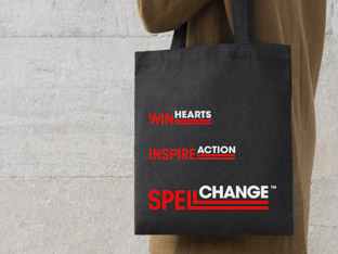 Person carrying a black tote bag with red and white Spell Change logo.