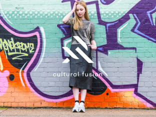 URTA logo mark, featuring interlocking U and A shapes, and the ‘Cultural Fusion’ tagline overlaid on top of the image of a young woman wearing fashionable clothes, standing in front of colourful graffiti.